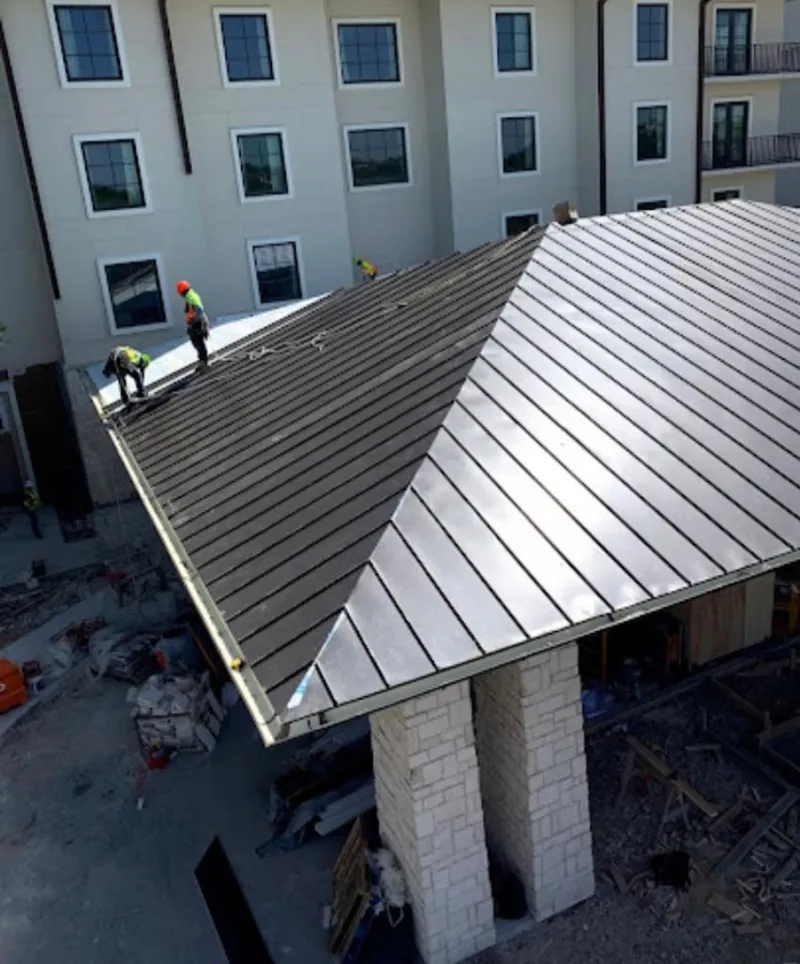 Crew installing standing seam metal roof panels on a commercial project in Greer